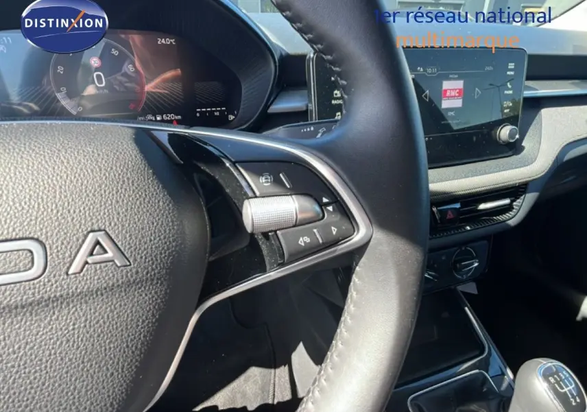 Vue intérieure centrée sur le volant et le tableau de bord de la Skoda Fabia noire, avec écran tactile et levier de vitesses manuel.