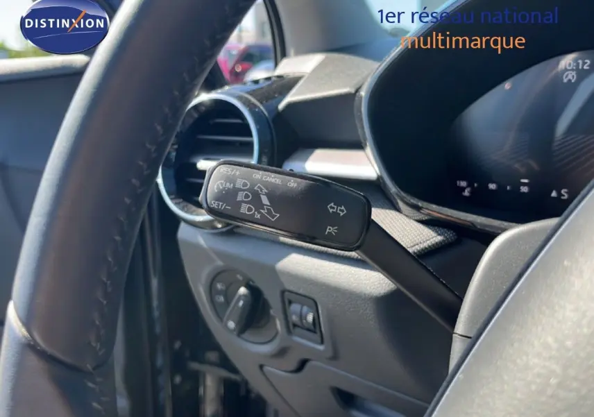 Gros plan sur la manette de commande du régulateur de vitesse à gauche du volant d’une Skoda Fabia noire, intérieur gris-noir.