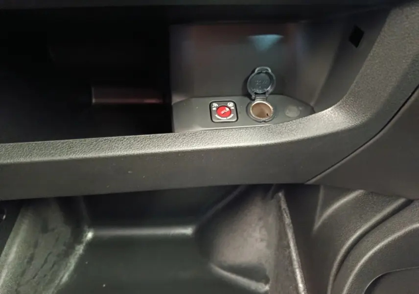 Gros plan sur la prise 12V et le bouton de commande dans le compartiment de rangement intérieur noir du Peugeot Expert Fourgon XL.