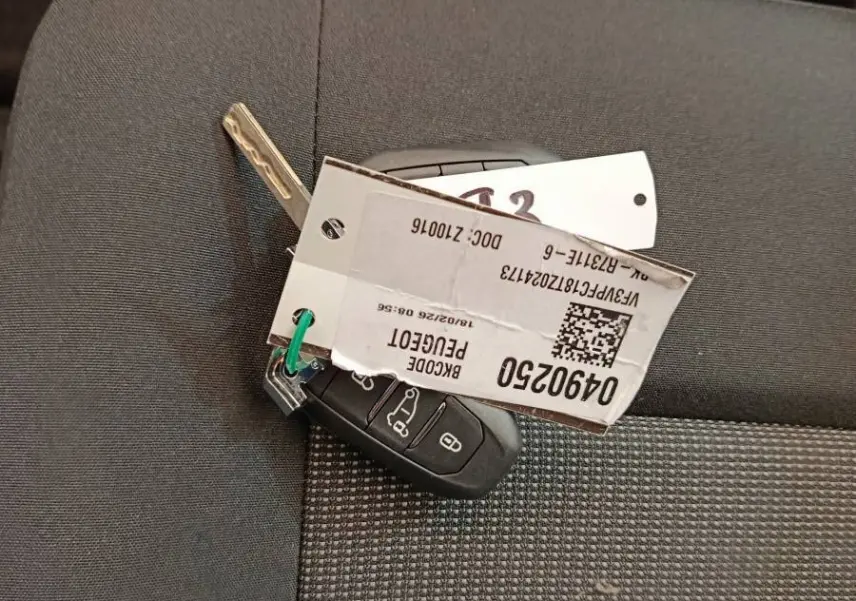 Clé de contact Peugeot Expert Fourgon XL Diesel posée sur un siège tissu gris foncé à motifs.