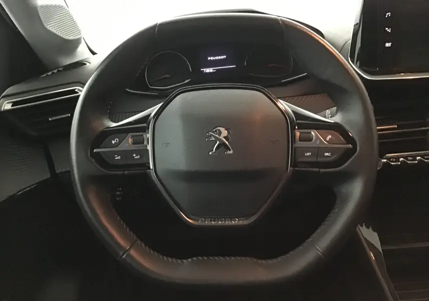 Volant en cuir noir de la Peugeot 208 1.2 PureTech 100 Style, avec commandes intégrées et tableau de bord numérique.