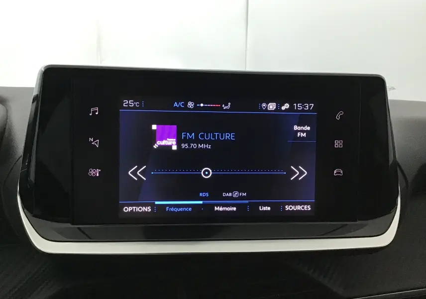 Écran tactile central du tableau de bord de la Peugeot 208 noire, affichant la radio FM Culture à 95,7 MHz.