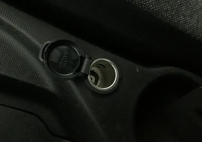 Prise 12V ouverte sur la console centrale intérieure d'une Peugeot 208 noire, version 1.2 PureTech 100 Style GPS S&S.