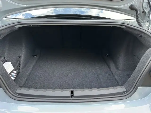 Coffre ouvert d'une BMW M2 G87 gris Brooklyn Grau, montrant un espace de rangement propre et spacieux.