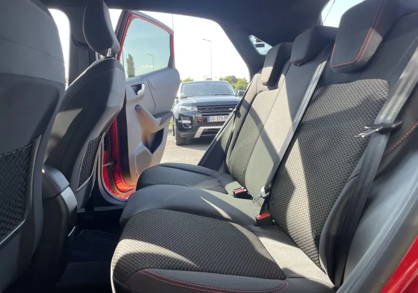Vue intérieure arrière droite du Ford Puma rouge 2021, montrant les sièges arrière en tissu noir avec surpiqûres rouges.