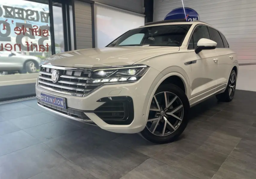 Vue 3/4 avant droite d'un Volkswagen Touareg blanc avec jantes alliage 20 pouces et calandre chromée R-Line.