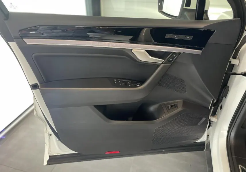 Vue intérieure de la porte avant gauche du Volkswagen Touareg blanc, avec garniture noire et inserts laqués piano.