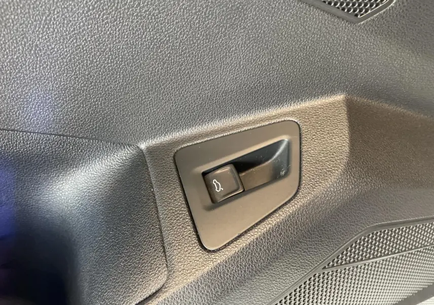 Bouton d'ouverture du hayon sur panneau intérieur noir texturé d'un Volkswagen Touareg blanc 2019.