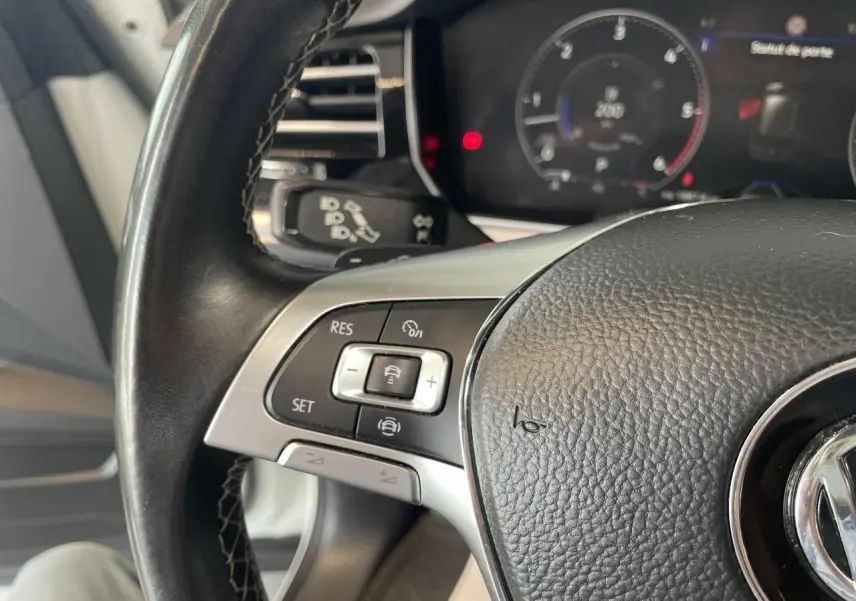 Gros plan sur le volant cuir noir multifonction R-Line du Volkswagen Touareg blanc, avec commandes de régulateur adaptatif visibles.