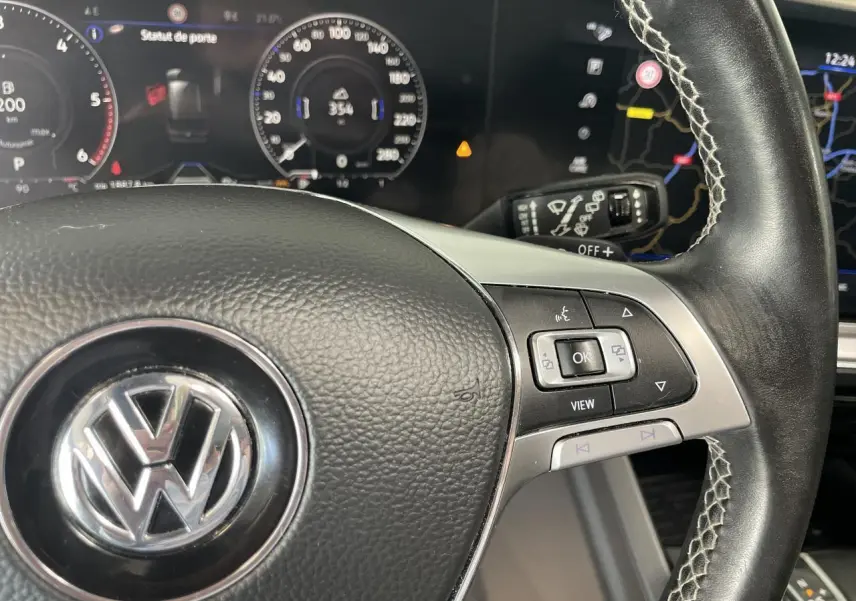 Gros plan sur le volant cuir noir R-Line avec commandes multifonctions et tableau de bord numérique du Volkswagen Touareg blanc.