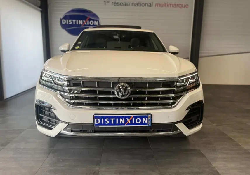 Vue frontale d'un Volkswagen Touareg blanc 2019 avec calandre chromée et logo R-Line visible sur le grillage.