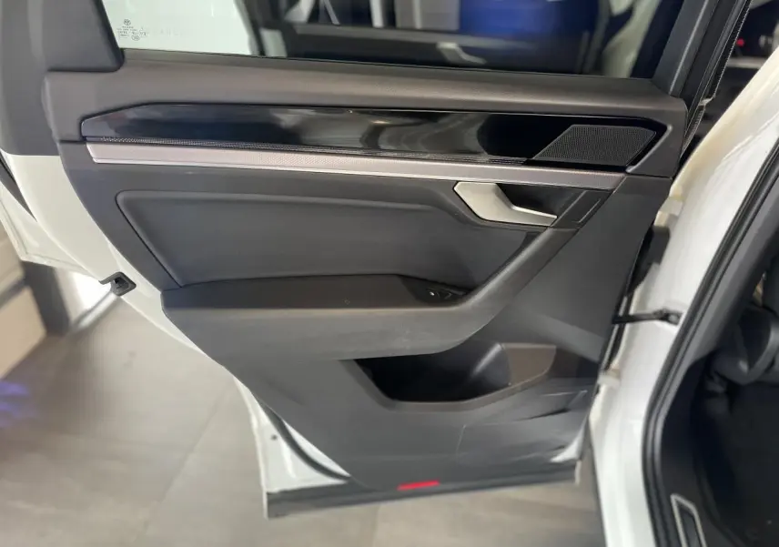 Porte avant droite ouverte d'un Volkswagen Touareg blanc, avec garniture noire et insert laqué piano.