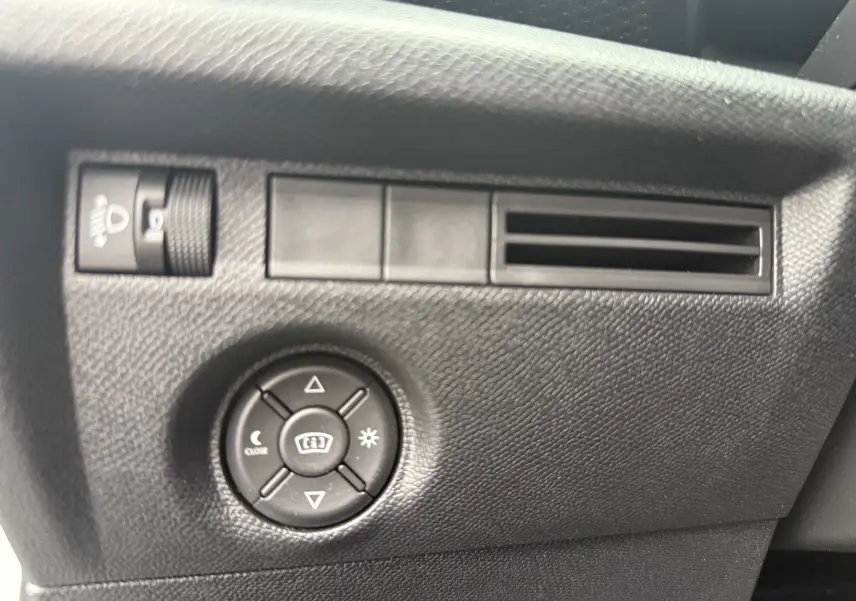 Détail du tableau de bord côté gauche de la Citroën C4 Hybrid 145 blanc Okenite, avec commandes d’éclairage et ventilation.