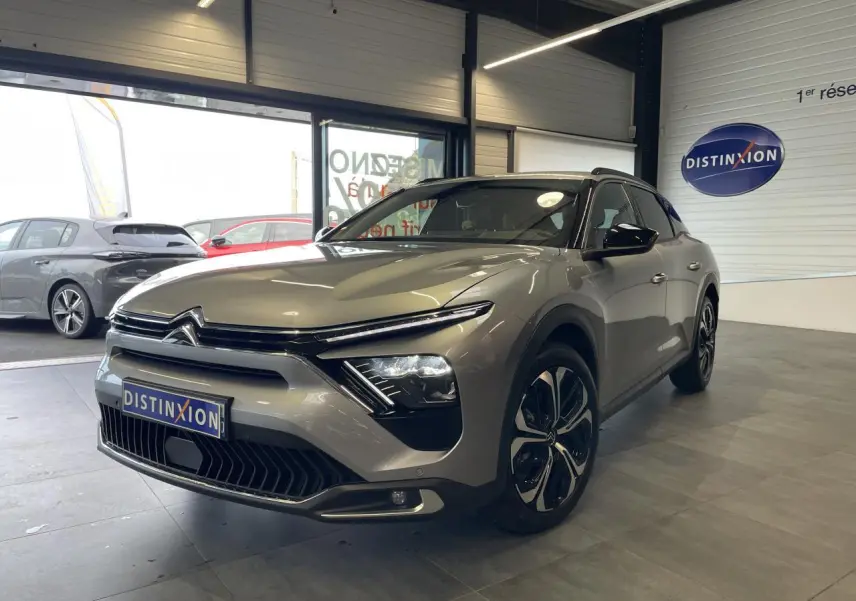 Citroën C5 X gris foncé vue 3/4 avant droit en intérieur, avec calandre distinctive et jantes modernes.