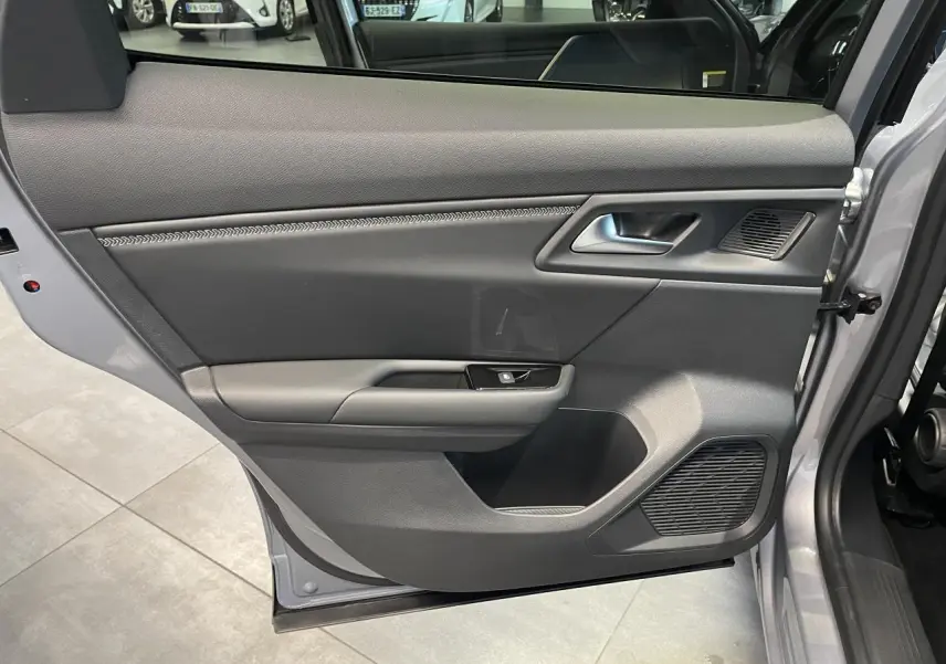 Vue intérieure de la porte avant gauche du Citroën C5 X gris foncé 2024, avec poignée argentée et haut-parleur intégré.