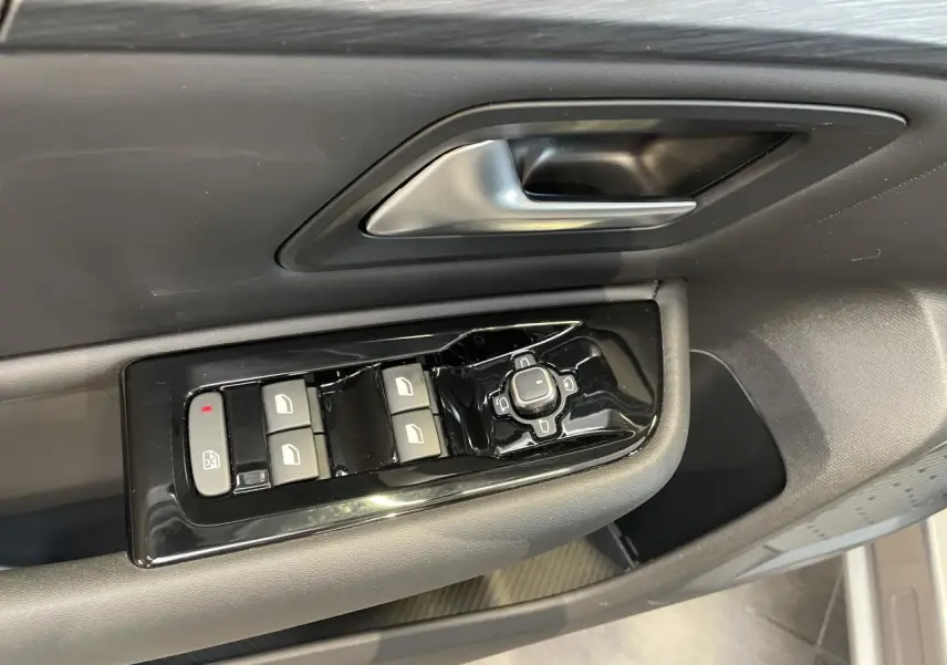 Gros plan sur la commande des vitres et rétroviseurs côté conducteur du Citroën C5 X 2024, intérieur gris foncé.