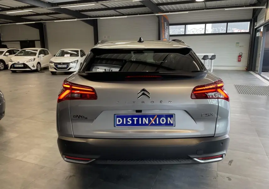 Vue arrière d'une Citroën C5 X gris foncé 2024 avec feux LED allumés dans un showroom intérieur.