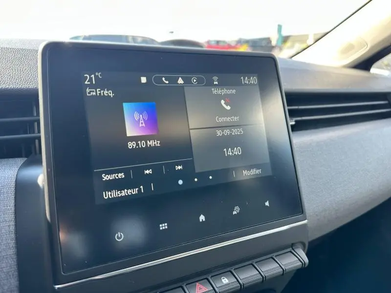 Écran tactile central de la Renault Clio 2025 affichant la radio et la connexion téléphone, vue intérieure côté passager.
