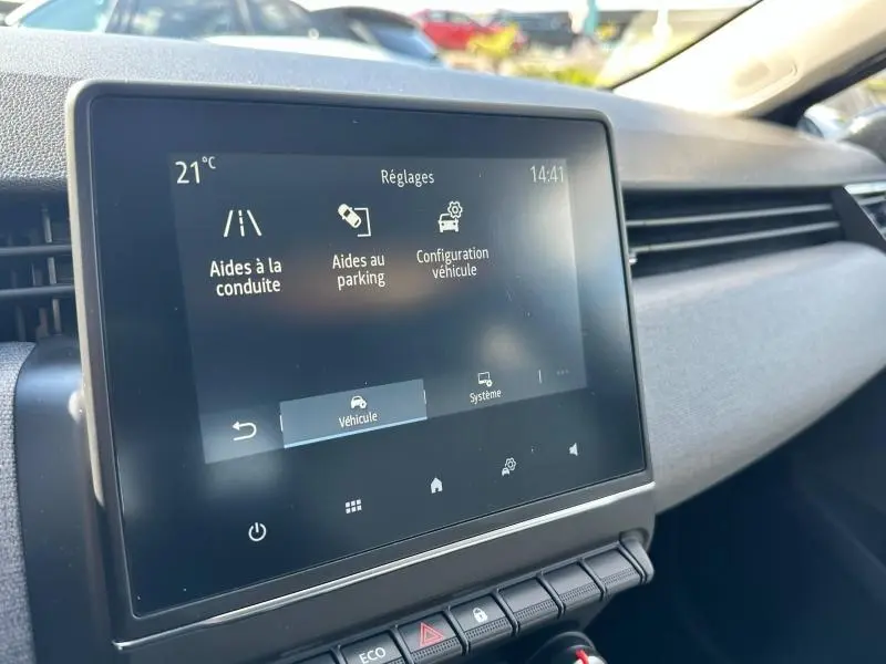 Écran tactile central de la Renault Clio gris Rafale, vue intérieure côté passager avec menu d’aides à la conduite affiché.