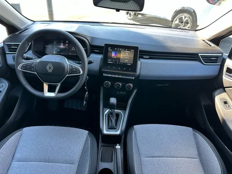 Vue intérieure avant de la Renault Clio 2025, tableau de bord et volant multifonction avec sellerie textile gris.