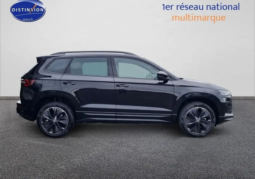 Profil côté gauche d'un SUV SKODA KAROQ noir 2025 avec jantes alu et barres de toit visibles.