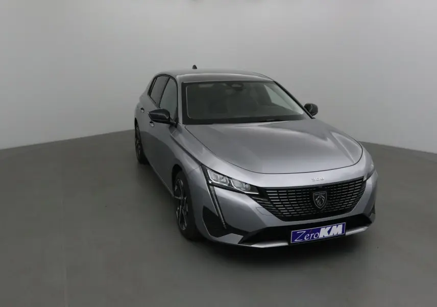 Peugeot 308 gris Artense vue 3/4 avant gauche dans un studio, avec calandre noire et feux LED distinctifs.