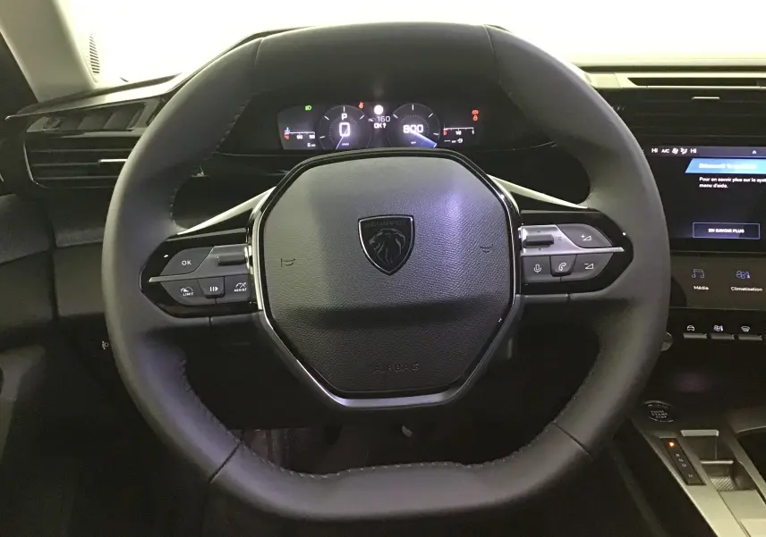 Volant cuir Peugeot 308 2025 avec commandes intégrées et tableau de bord numérique visible en arrière-plan.