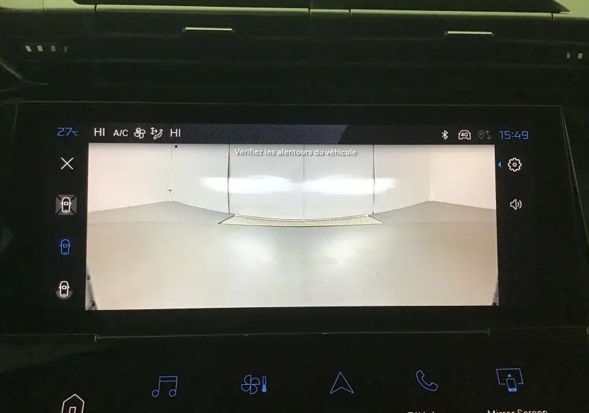 Écran de caméra 360 affichant la vue arrière du Peugeot 308 gris Artense avec consigne de vigilance aux alentours.