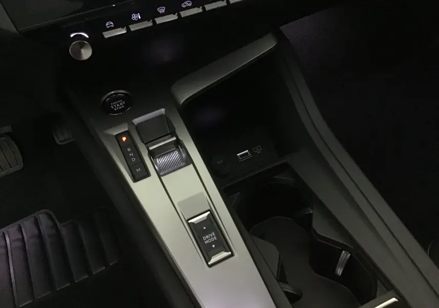 Gros plan sur la console centrale de la Peugeot 308 gris Artense, montrant la commande de boîte auto et le bouton Drive Mode.