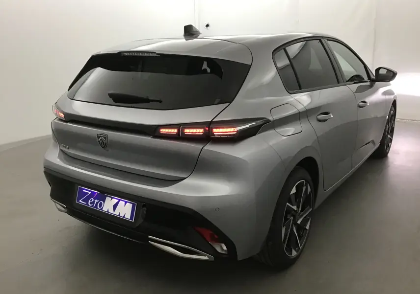 Peugeot 308 gris Artense vue 3/4 arrière droit, feux arrière allumés et jantes alliage distinctives.