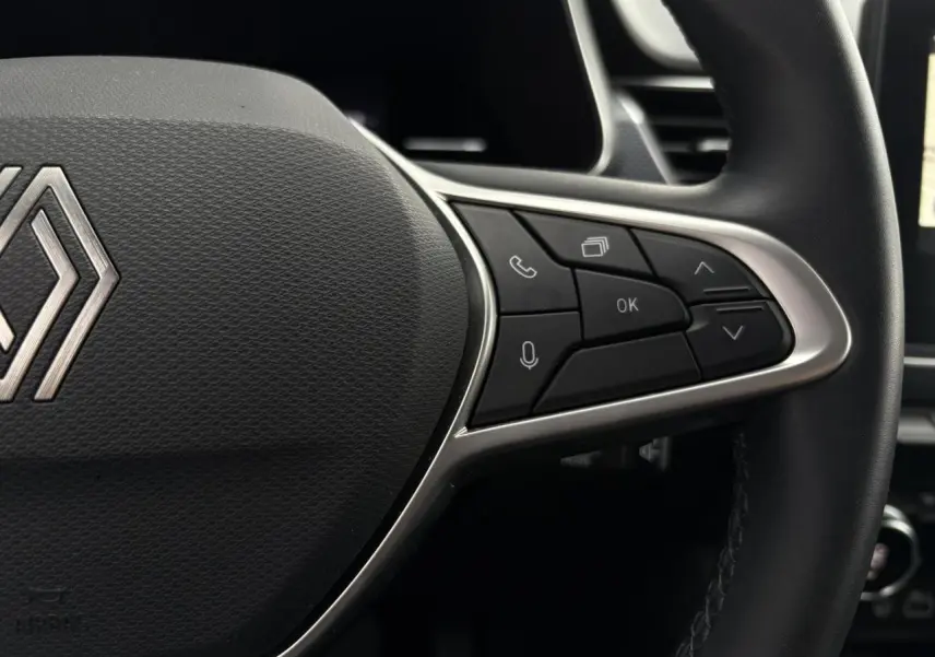Gros plan sur le volant en textile grainé du Renault Arkana 2025, montrant les commandes multifonctions à droite.