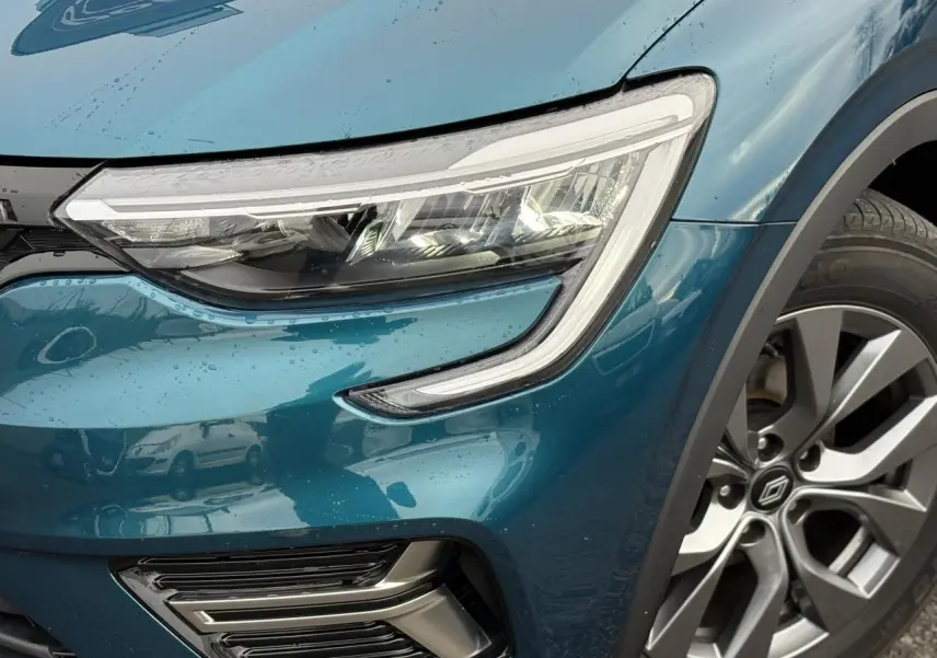 Gros plan sur l'avant droit bleu Zanzibar du Renault Arkana 2025, mettant en valeur le phare LED et la jante alliage 17 pouces.