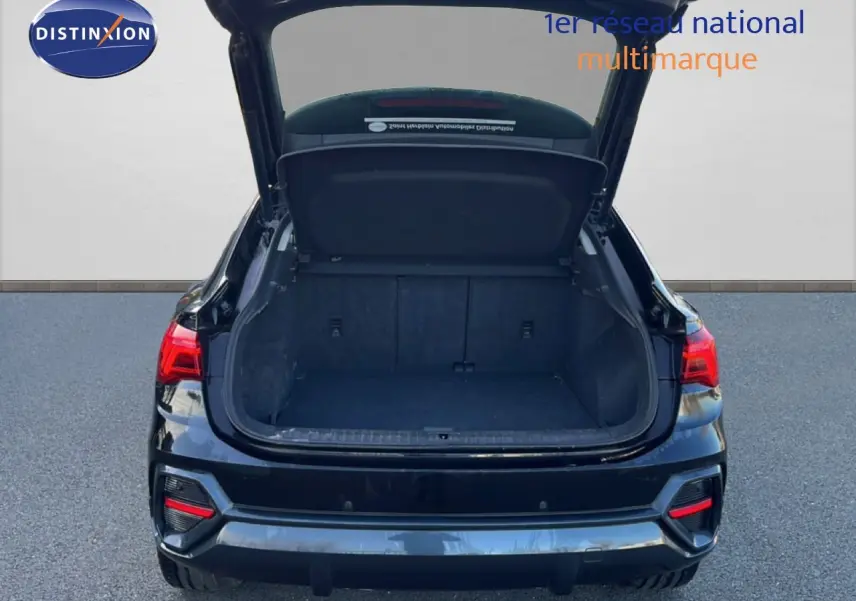 Vue arrière d’un Audi Q3 Sportback noir 2022 avec coffre ouvert montrant l’espace de chargement vide.