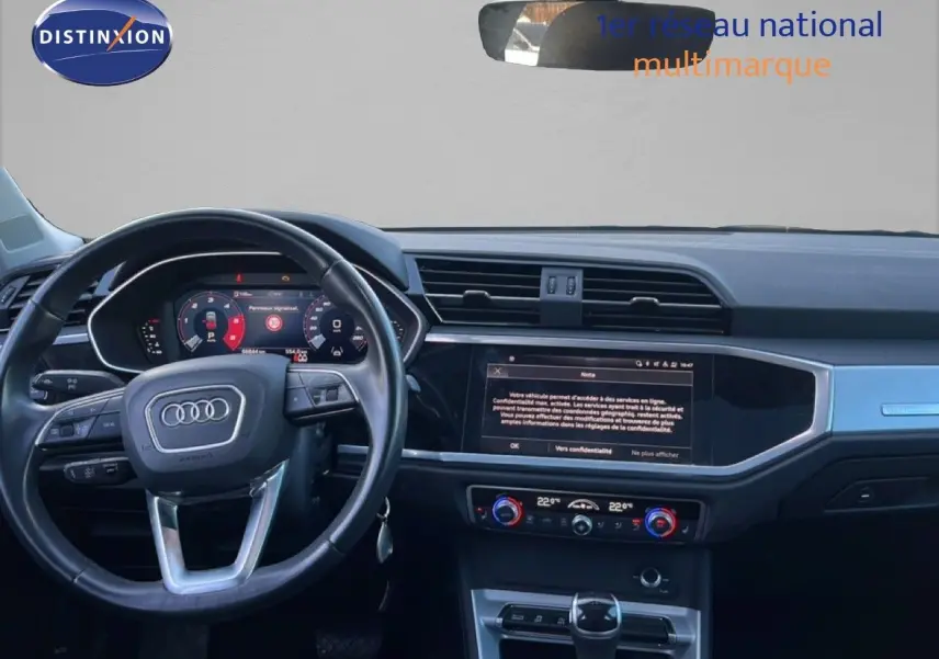 Vue intérieure de face du tableau de bord d’un Audi Q3 Sportback noir 2022, avec volant multifonction et écran tactile central.