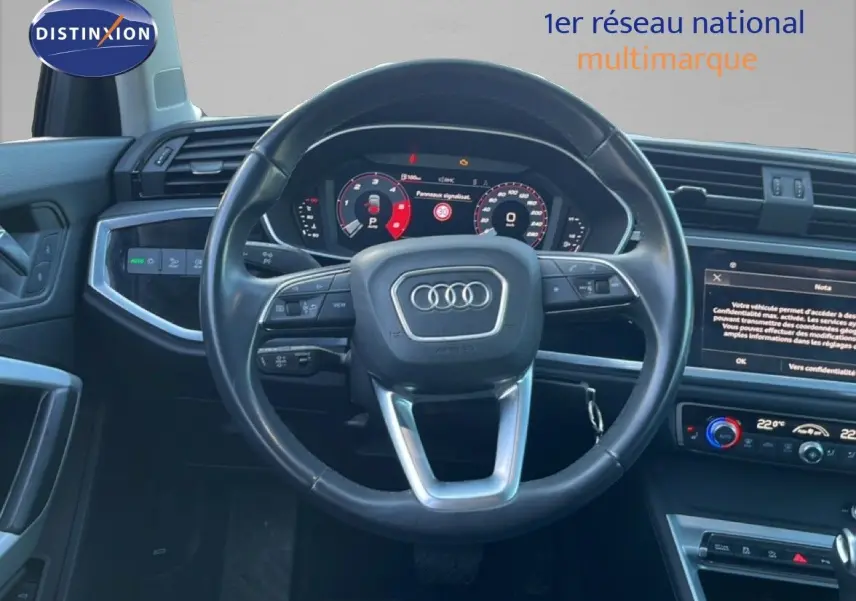 Vue intérieure centrée sur le volant et le tableau de bord numérique d’un Audi Q3 Sportback noir de 2022.