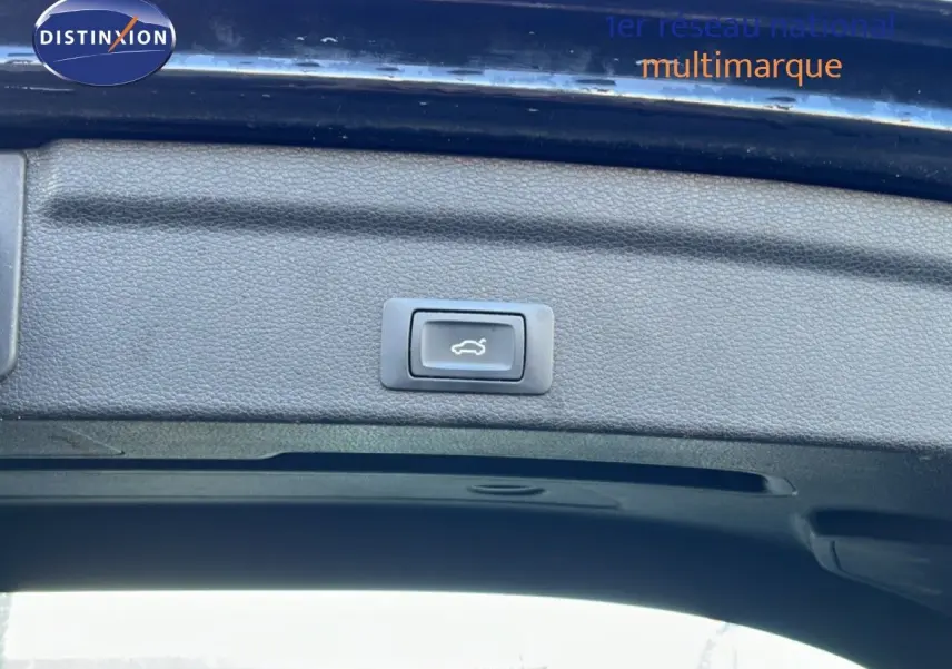 Bouton d'ouverture électrique du coffre sur la partie intérieure du hayon arrière d'un Audi Q3 Sportback noir, vue rapprochée.