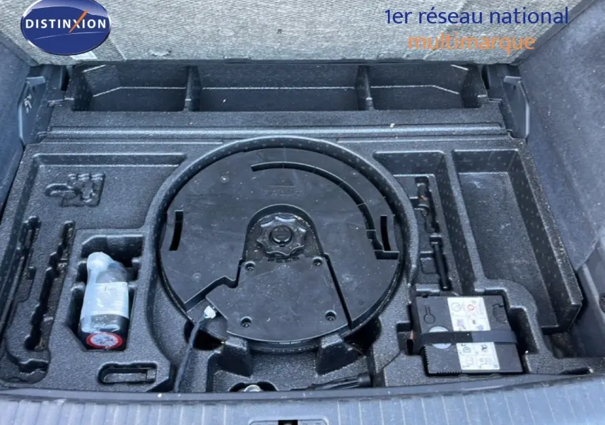 Coffre ouvert montrant le rangement noir avec kit de réparation et emplacement roue de secours de l'Audi Q3 Sportback noir.
