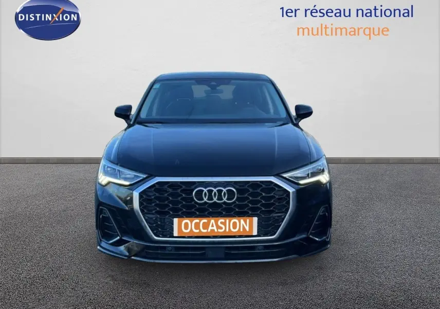 Vue de face d'un Audi Q3 Sportback noir 2022 avec calandre hexagonale et phares LED allumés.