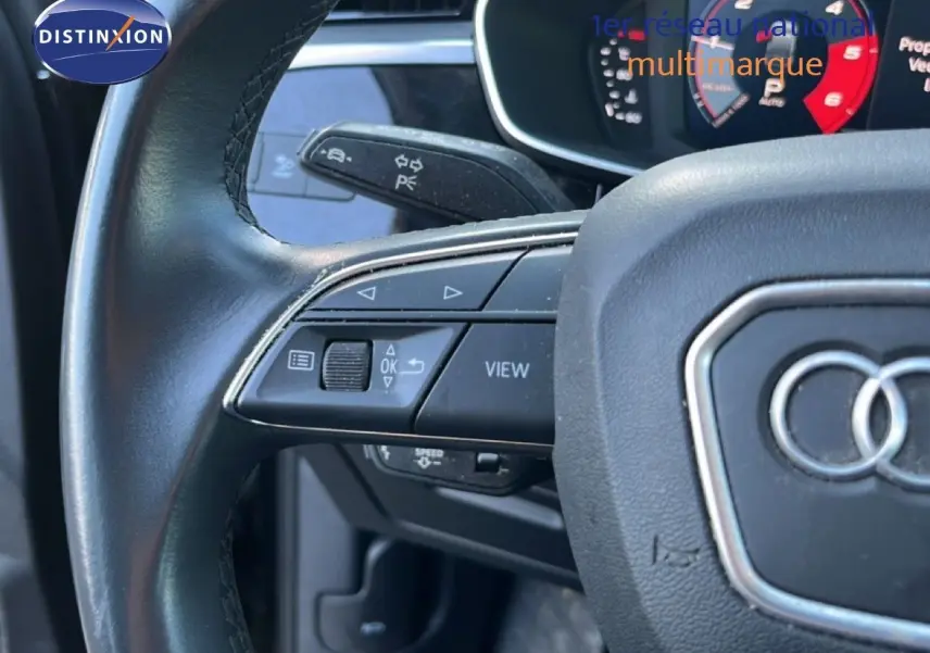 Gros plan sur le volant noir de l'Audi Q3 Sportback 35 TDI 150 S-Line avec commandes intégrées et logo Audi visible.