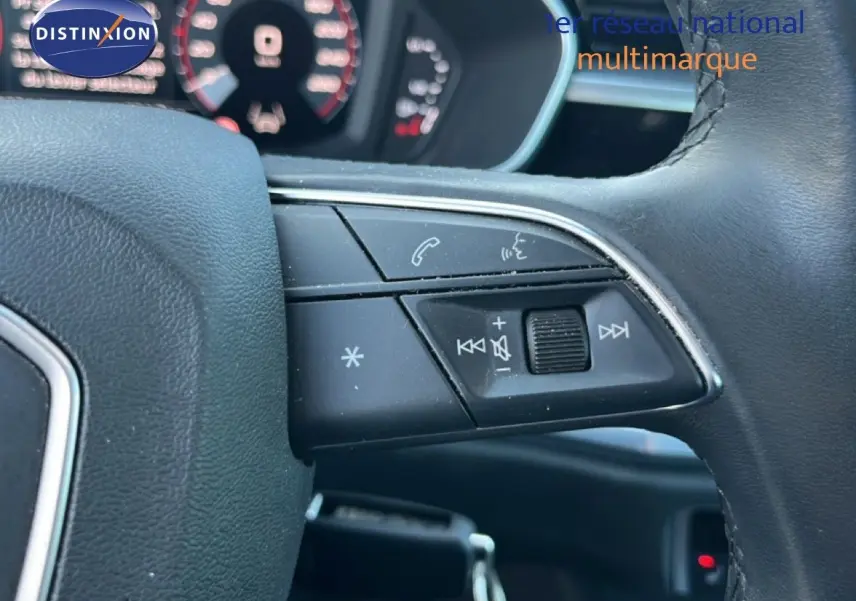 Gros plan sur les commandes au volant côté droit de l'Audi Q3 Sportback noir 2022, avec tableau de bord flou en arrière-plan.
