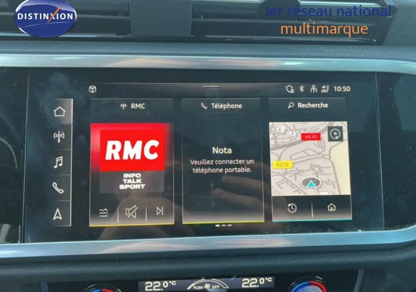 Vue rapprochée de l’écran tactile noir de l’Audi Q3 Sportback 2022 affichant la radio RMC et la navigation.
