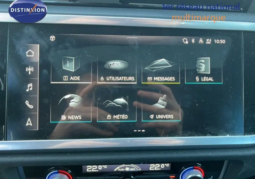 Vue intérieure centrée sur l'écran tactile et la console de climatisation du tableau de bord de l'Audi Q3 Sportback noir.