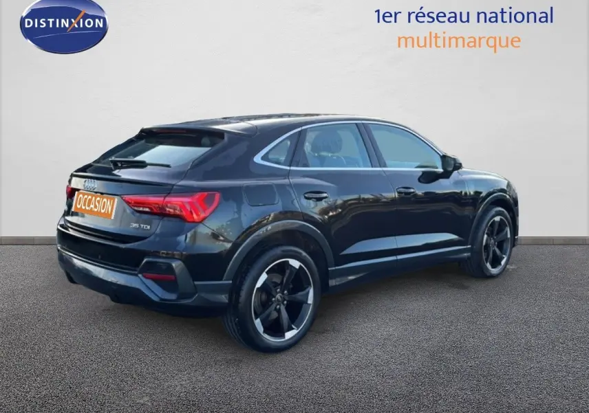 Audi Q3 Sportback noir vue 3/4 arrière côté droit, avec jantes noires distinctives et feux arrière allumés.