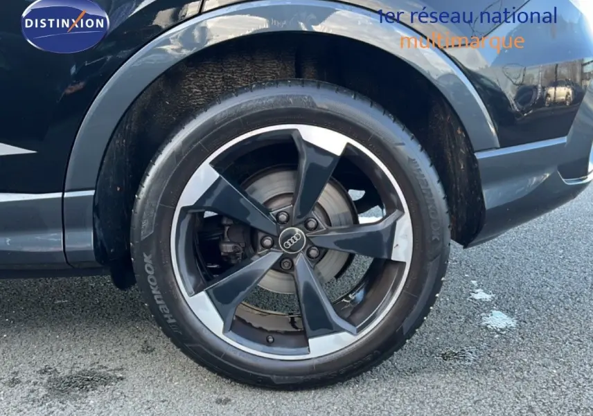 Gros plan sur la roue avant droite noire d’un Audi Q3 Sportback 35 TDI 150 S-Line avec jante alliage bicolore.