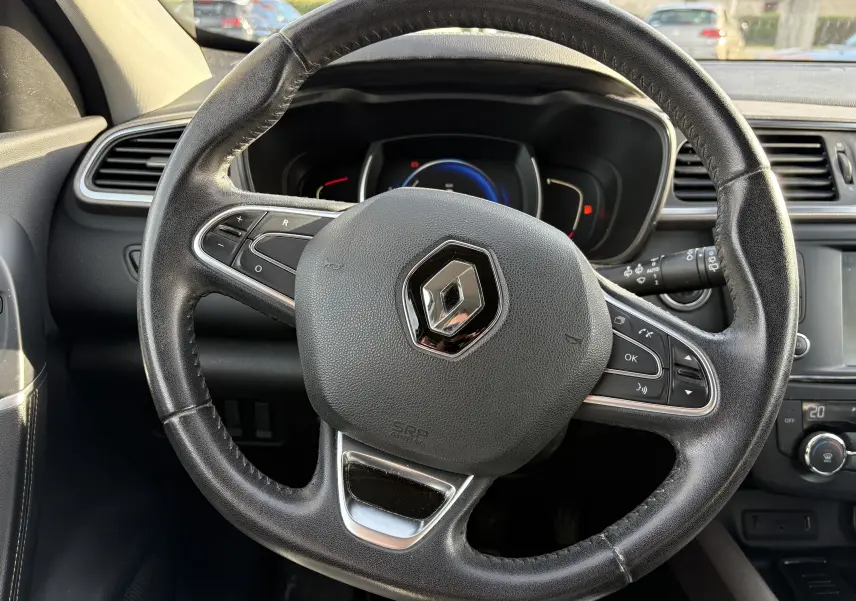 Gros plan sur le volant en cuir noir avec logo Renault, tableau de bord et commandes visibles dans un Renault Kadjar 2015.