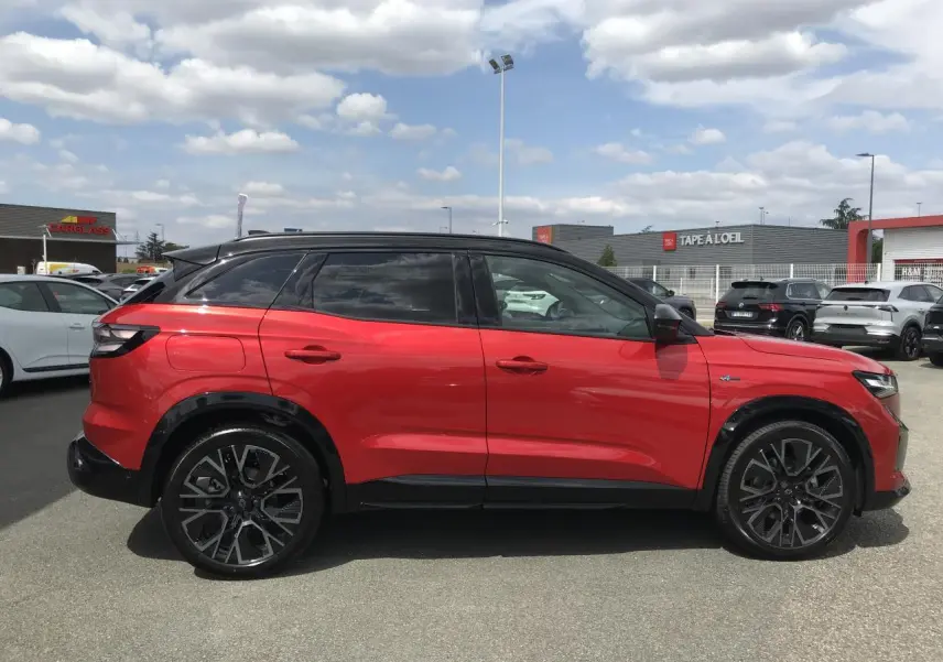 Vue de profil côté gauche d'un Renault Austral 2025 bi-ton rouge et noir avec jantes alliage noires diamantées.