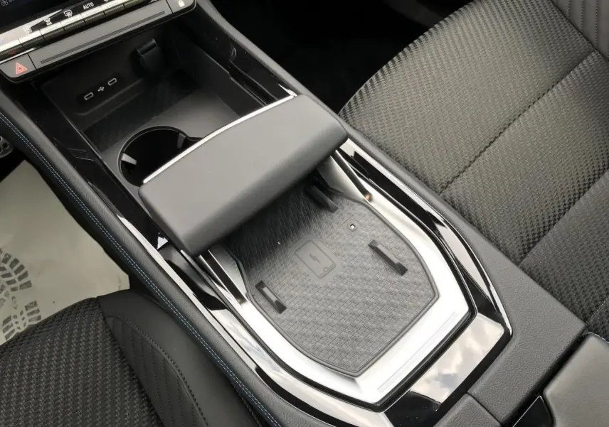 Vue plongeante sur la console centrale noire du Renault Austral hybride avec chargeur smartphone à induction et sellerie tissu noire.