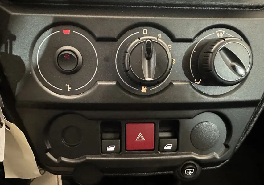 Gros plan sur les commandes de climatisation et les boutons de l’Aixam Ambition E City Pack 2026, tableau de bord noir.