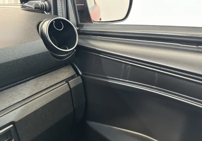 Détail intérieur côté conducteur montrant la sortie d'air ronde et le rétroviseur extérieur caméra d'une Aixam Ambition E City Pack rouge.