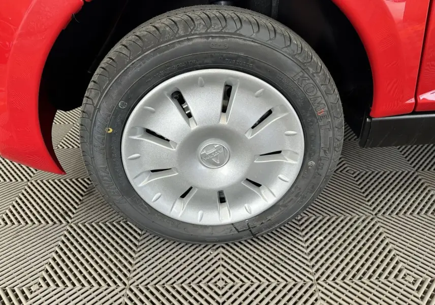 Gros plan sur la roue avant gauche d'une Aixam Ambition E City Pack rouge, avec jante argentée et pneu Komet Plus.